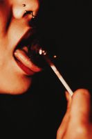 Woman with nose ring licking a lollipop